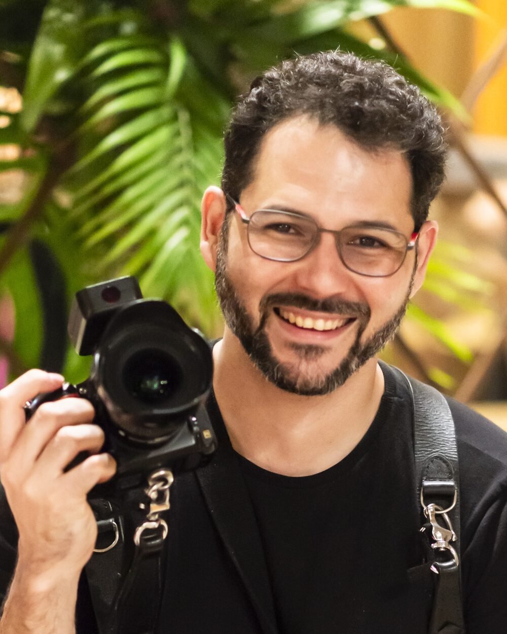 José Júnior, fotógrafo, sorrindo com sua câmera profissional